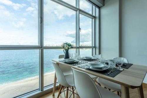 a dining room with a table and chairs with a view of the ocean at APARTAMENTO CON INCREIBLES VISTAS A LA PLAYA DE RIAZOR in A Coruña