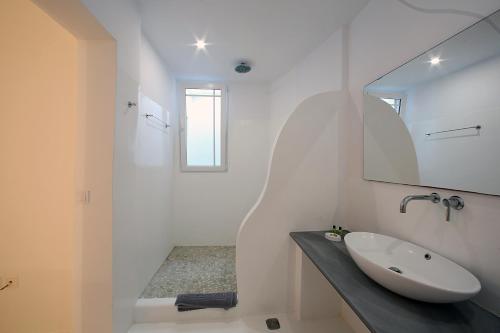 Baño blanco con lavabo y espejo en Blue Ocean Mykonos, en Ornos