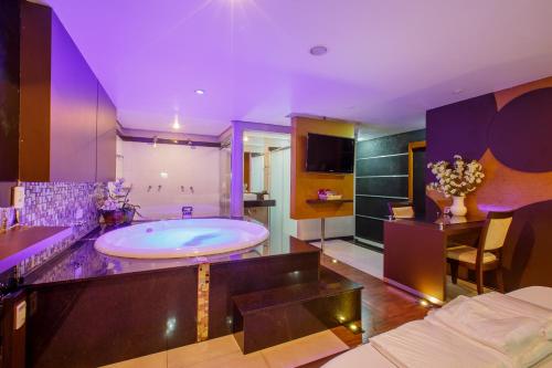 a large bathroom with a large tub and purple lighting at Motel Fascínio (Only Adults) in Cascavel