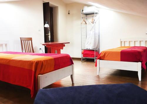 a room with two beds with red and orange sheets at AURIGA in Pietrapertosa