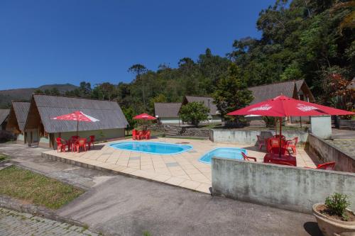 una piscina con tavoli, sedie e ombrelloni di Hotel Shangrila Nova Friburgo a Nova Friburgo