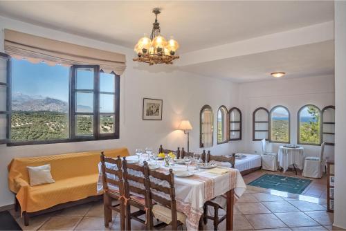 a dining room with a table and chairs and windows at Charming Country House with View in Episkopí- Rethimno