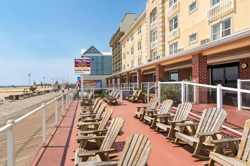 a row of chairs sitting on a sidewalk next to a beach at Plim Plaza Hotel in Ocean City