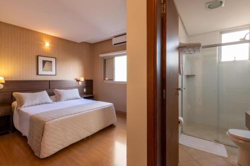a bedroom with a bed and a bathroom with a shower at Hotel Bahamas in Dourados