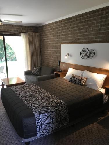 Habitación de hotel con cama y sofá en Idlewilde Town & Country Motor Inn, en Pambula