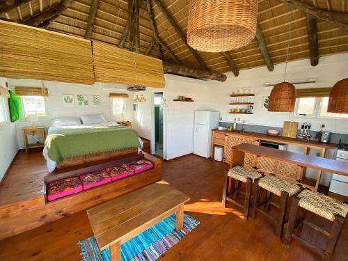 a bedroom with a bed and a kitchen in a room at Cabañas Punta Papaya in Punta Del Diablo