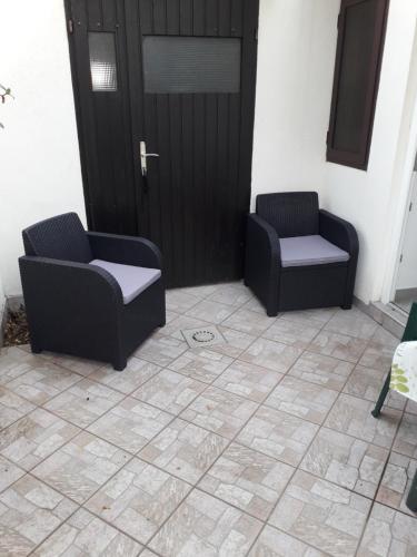 two chairs sitting in front of a door at Apartments Lidija in Pag