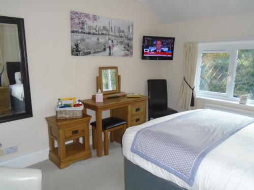 a bedroom with a bed and a desk with a mirror at Trumbles Gatwick B&B in Charlwood
