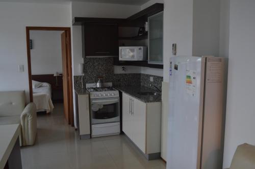 
a kitchen with a refrigerator, stove, sink and a microwave at Apart Riviera Tower Suites in Villa Carlos Paz
