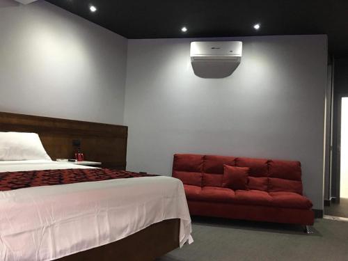 a bedroom with a bed and a red couch at Motel Boutique Xpress in Ensenada