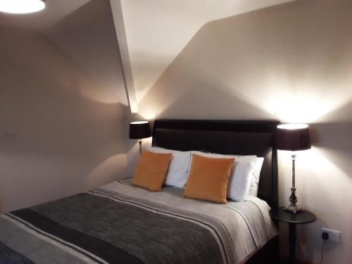 a bedroom with a bed with two orange pillows at Shannonside Studios in Athlone