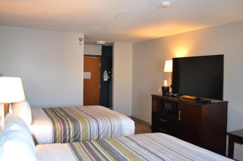 a hotel room with two beds and a flat screen tv at Country Inn & Suites by Radisson, Fairview Heights, IL in Fairview Heights