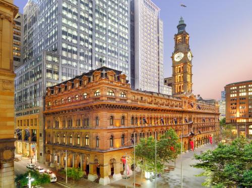 un antiguo edificio con una torre de reloj en una ciudad en The Fullerton Hotel Sydney, en Sídney