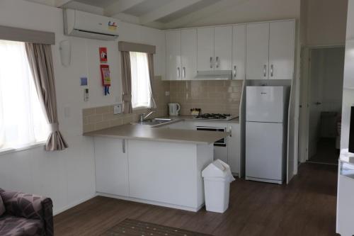 a kitchen with white cabinets and a white refrigerator at Jenolan Holiday Park Oberon in Oberon