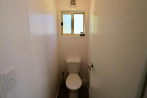 a small bathroom with a toilet and a window at Jenolan Holiday Park Oberon in Oberon