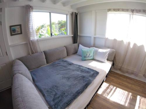 a couch in a living room with a window at Somewhere over the Rainbow Loft with AC Hilo in Hilo