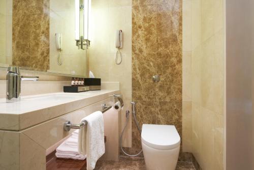 a bathroom with a toilet and a sink and a mirror at Holiday Inn Singapore Little India by IHG in Singapore