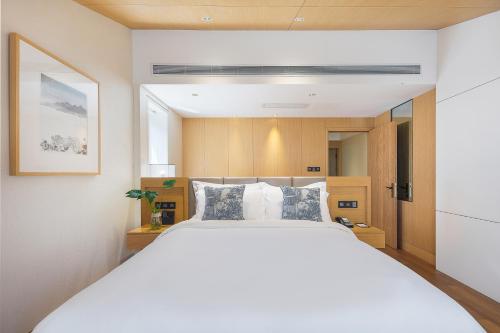 a bedroom with a large white bed with blue pillows at Floral Hotel ·Hefu Hotel (Hangzhou West Lake) in Hangzhou
