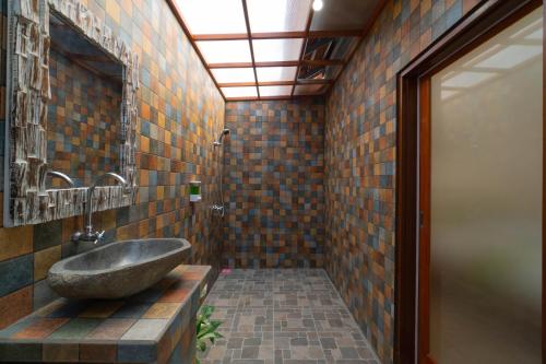 a bathroom with a stone sink and a mirror at Uluwatu Kayana Bungalows by Bukit Vista in Uluwatu