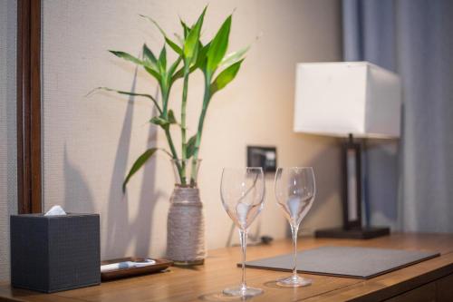 two wine glasses sitting on a table with a vase at Floral Hotel ·Hefu Hotel (Hangzhou West Lake) in Hangzhou