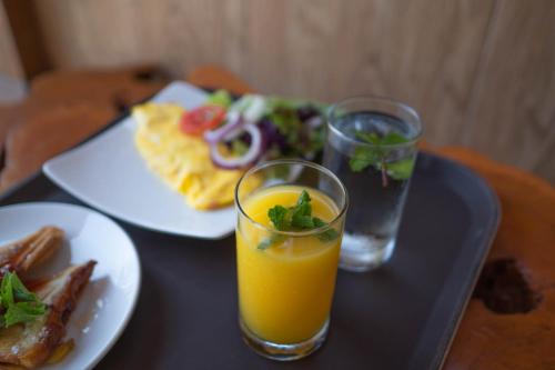 a tray with two glasses of orange juice and a plate of food at Uluwatu Kayana Bungalows by Bukit Vista in Uluwatu