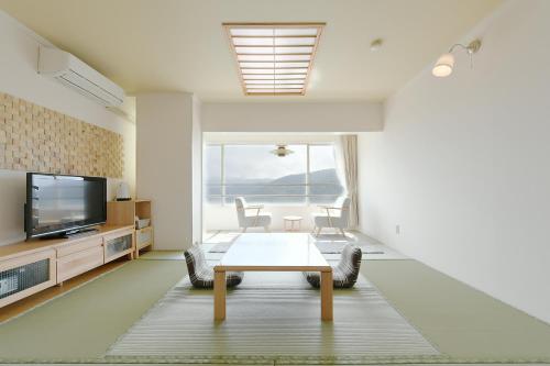 a living room with a table and a tv at Hotel Ra Kuun in Hakone