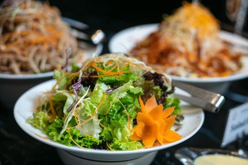 a salad in a bowl on a table with other plates of food at Imperial Hotel & Spa in Hanoi