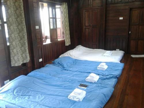 Una cama con sábanas azules y toallas blancas. en บ้านฟ้ารักตะวัน en Cha Am