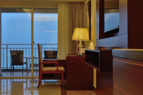 a room with a desk and a chair and a balcony at Wyndham Garden Wenchang Nanguo in Wenchang