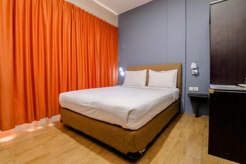 瑟古邦Blitz Hotel Batam Near Sultan Mahmud Ri'ayat Shah的一间卧室配有一张带橙色窗帘的床