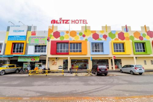 a colorful building with cars parked in a parking lot at Blitz Hotel Batam Near Sultan Mahmud Ri'ayat Shah in Sekupang