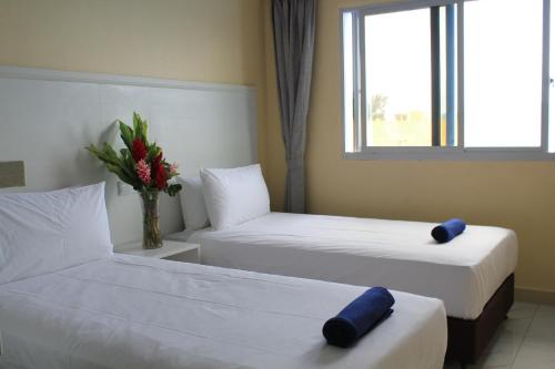 a hotel room with two beds and a vase of flowers at Central Bay Motel in Port Vila