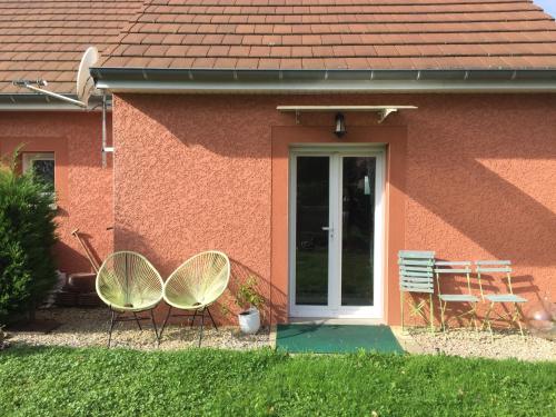 dos sillas sentadas fuera de una casa con una puerta en Maison à la Campagne à 2km du Circuit de Bresse, en Sagy