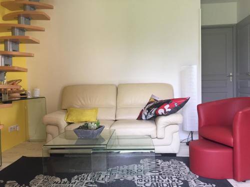 sala de estar con sofá blanco y silla roja en Maison à la Campagne à 2km du Circuit de Bresse, en Sagy