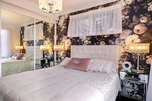 a bedroom with a white bed and floral wallpaper at Valley View Bed and Breakfast in Newcastle