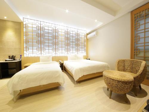 a bedroom with two beds and a chair and a window at Almond Hotel Busan Station in Busan