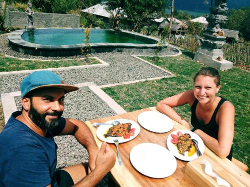 a man and woman sitting at a table with plates of food at Batur Pyramid Guesthouse in Kintamani