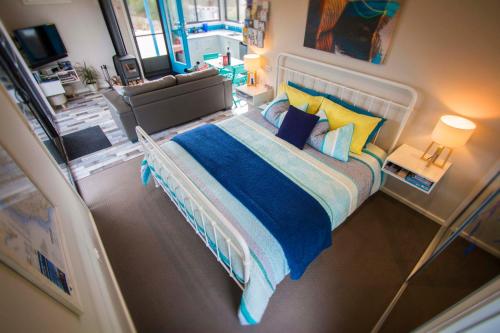 a bedroom with a large bed with blue and yellow pillows at Coorong Cabins in Meningie