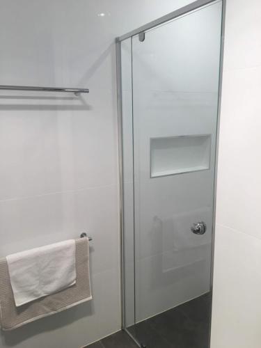 - szklane drzwi do prysznica w łazience z ręcznikiem w obiekcie Central apartment with stairs w mieście Ballarat