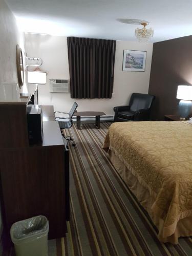 a hotel room with a bed and a desk and chairs at Super 8 by Wyndham Shelton in Shelton
