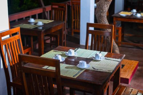 una mesa de madera y sillas con tazas y platillos. en Thammenna Eco Cabins, en Dambulla