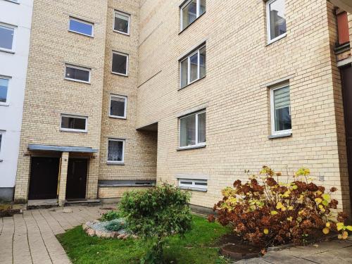 a large brick building with a yard in front of it at Nikoletos apartamentai in Panevėžys