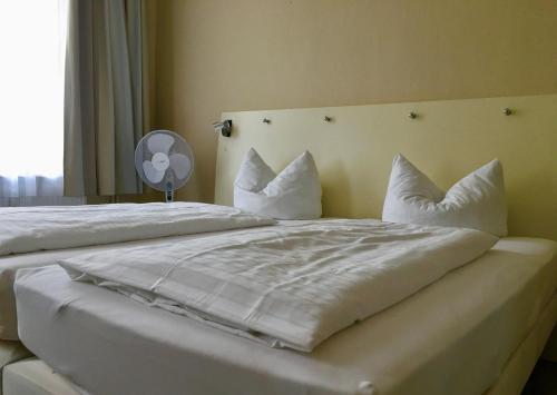 ein großes Bett mit weißer Bettwäsche und Kissen in der Unterkunft Pension am Pollingpark Haus II in Dessau