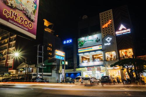 a busy city street at night with neon signs at The Alts Hotel in Palembang