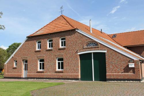 un edificio de ladrillo rojo con una puerta verde en Ferienwohnung im Gulfhof, 65269, en Moormerland