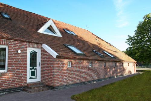 un edificio de ladrillo rojo con techo y ventanas en Ferienwohnung im Gulfhof, 65269, en Moormerland