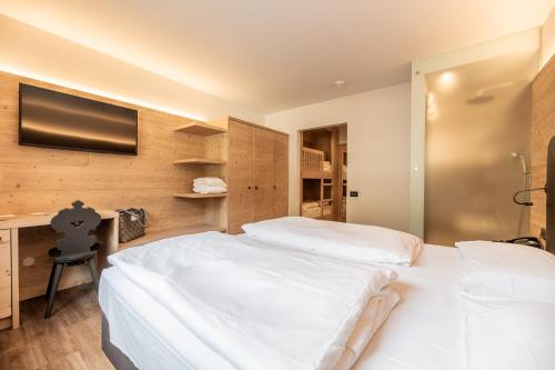 a bedroom with two white beds and a flat screen tv at Ravelli Sporting in Mezzana