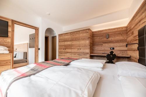 two white beds in a bedroom with wooden walls at Ravelli Sporting in Mezzana