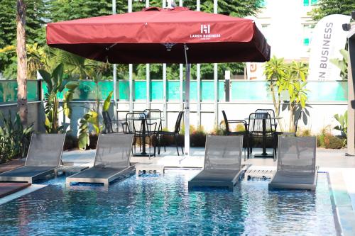 una piscina con sillas, sombrilla roja, mesa y sillas en Laren Sea Side Hotel Spa, en Antalya