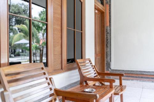 two wooden chairs and a wooden table in front of a window at Bendesa Accommodation in Kuta